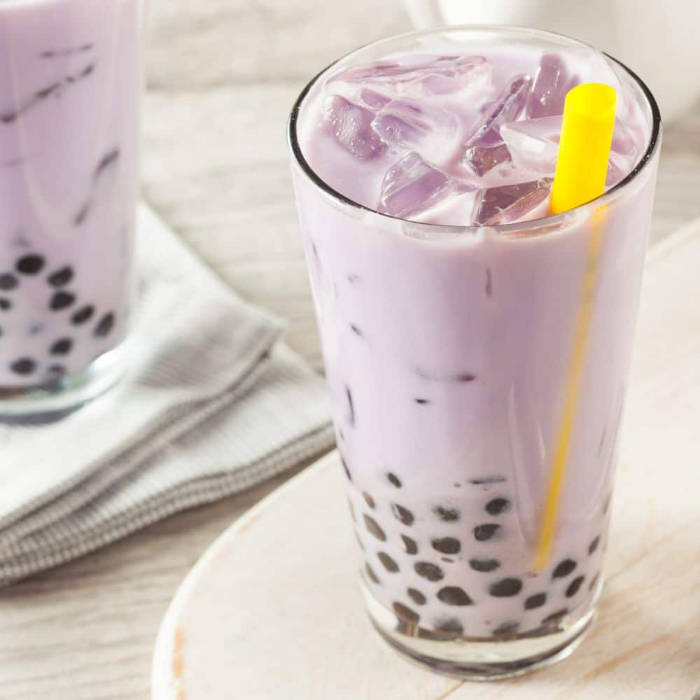 purple boba tea in glass cup with yellow straw